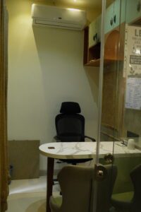 Private cabin workspace with a black ergonomic chair, marble desk, and wall-mounted air conditioner in a coworking office.