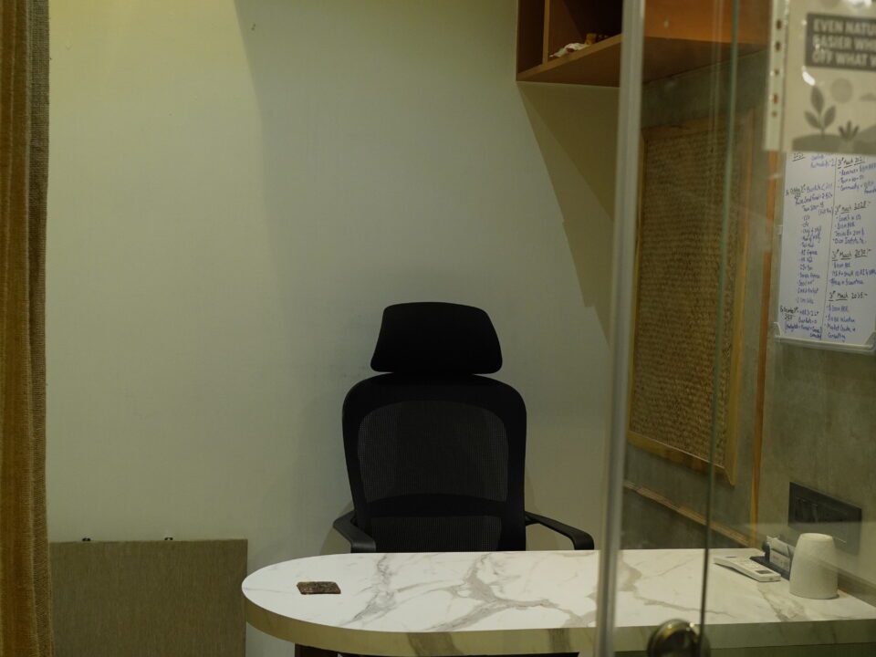 Private cabin workspace with a black ergonomic chair, marble desk, and wall-mounted air conditioner in a coworking office.
