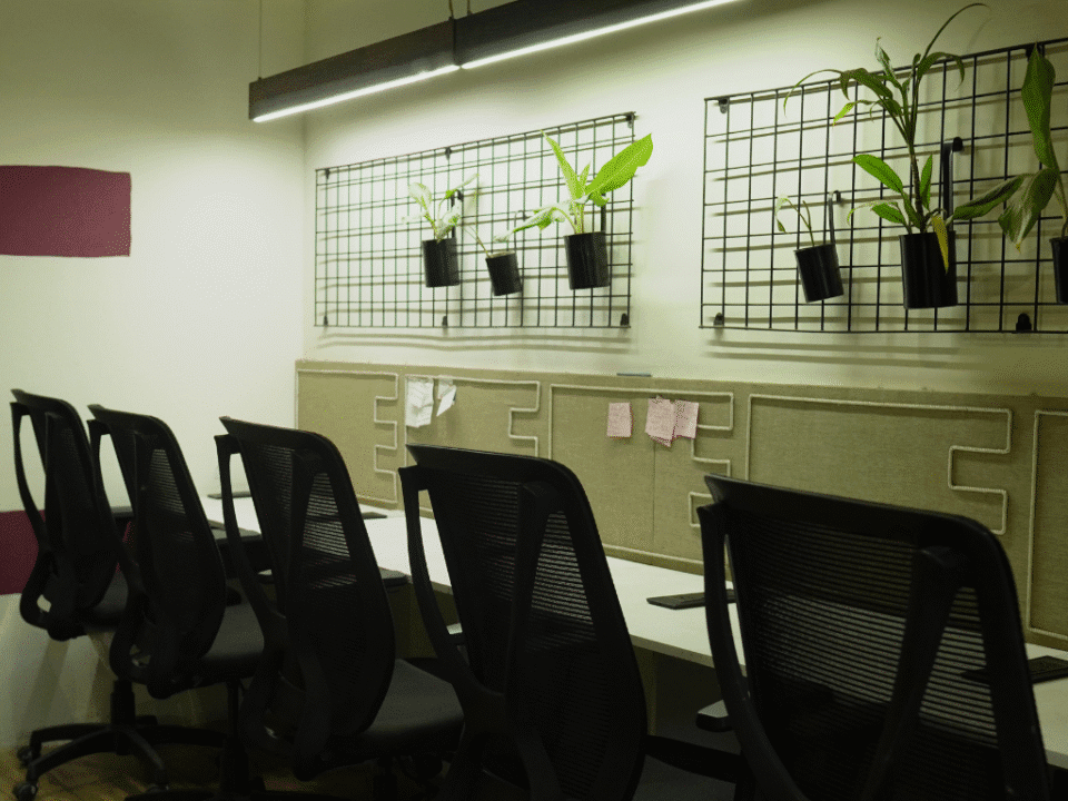Modern coworking space with ergonomic office chairs, desk plants, and a sleek, well-lit workspace wall at Estancia Coworking in Indore.